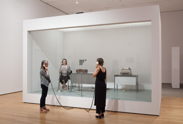 David Lamelas. Office of Information about the Vietnam War at Three Levels: The Visual Image, Text and Audio. 1968/2015. Office furniture, telex, tape recorder, microphone, telephone receivers, text, Plexiglas partition, and performance. The Museum of Modern Art, New York. Gift of the artist and Jan Mot, Brussels. © 2015 David Lamelas. Performance view, Transmissions: Art in Eastern Europe and Latin America, 1960–1980, The Museum of Modern Art, September 5, 2015–January 3, 2016. Performer: Patrisa Tomassini. Digital image © 2015 The Museum of Modern Art. Photo: Thomas Griesel