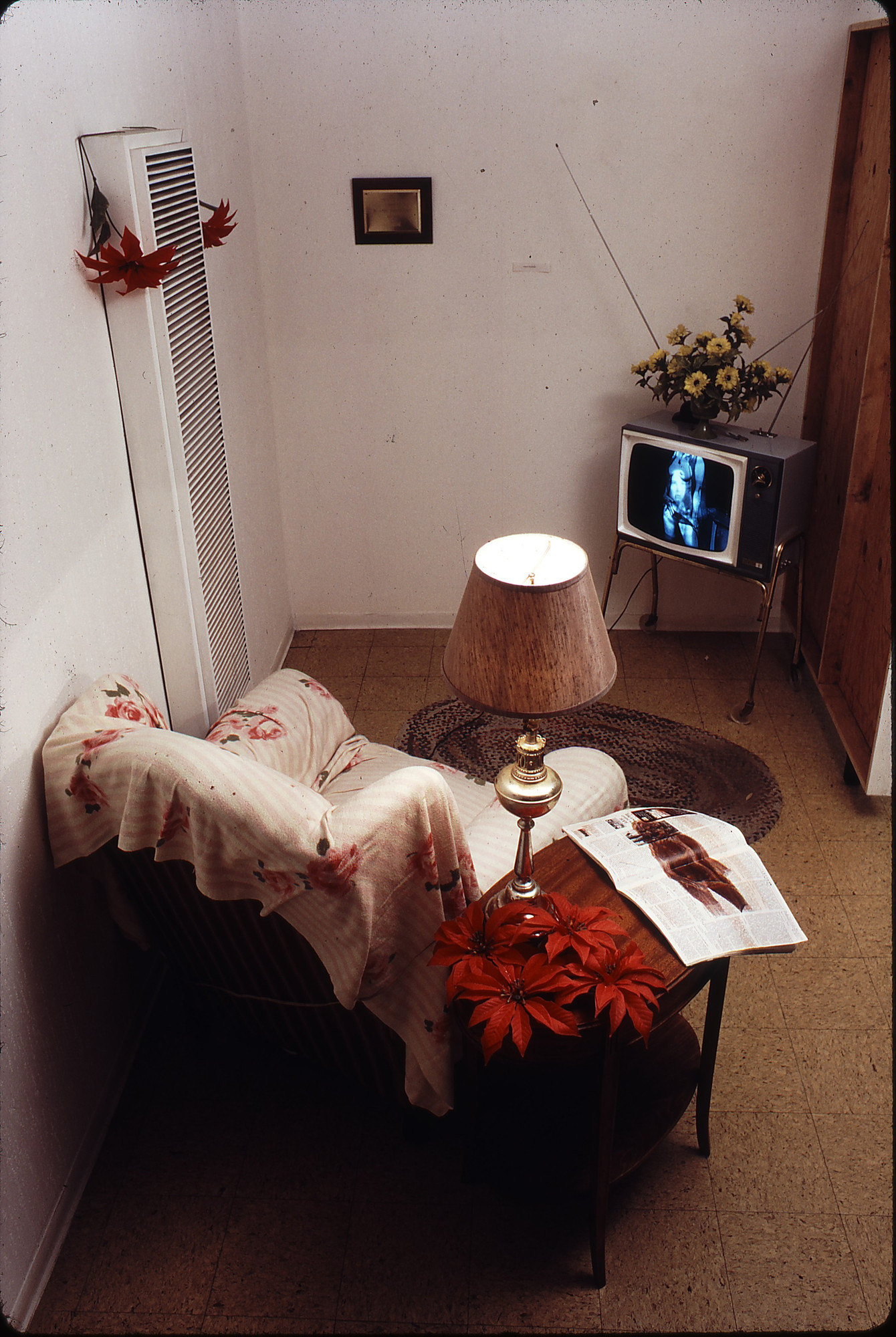 Robert Heinecken. _TV/Time Environment_. 1970. Functioning television set, film transparency, chair, rug, plastic plant, and related magazine, dimensions variable. Center for Creative Photography, University of Arizona, Tucson. Robert Heinecken Archive. Gift of the artist. © 2014 The Robert Heinecken Trust