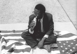 Pope.L, Eating the Wall Street Journal, early street version. 1991. © Pope.L. Courtesy the artist