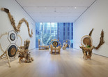 Installation view of the gallery "Guadalupe Maravilla: Luz y Fuerza" in the exhibition "Collection 1970s–Present,” October 30, 2021 - October 30, 2022. The Museum of Modern Art, New York. Digital Image ©️ 2022 The Museum of Modern Art, New York. Photo: David Almeida Image description: A photograph of seven sculptures made out of natural materials by the artist Guadalupe Maravilla, installed on the floor and the walls of a MoMA gallery.