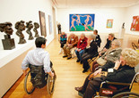Photo: Jason Brownrigg ©️ 2023 The Museum of Modern Art, New York. Image description: An educator in conversation with a seated group of 10 adults facing a display of four sculpted bronze busts by the artist Henri Matisse in a gallery with colorful paintings on the wall.