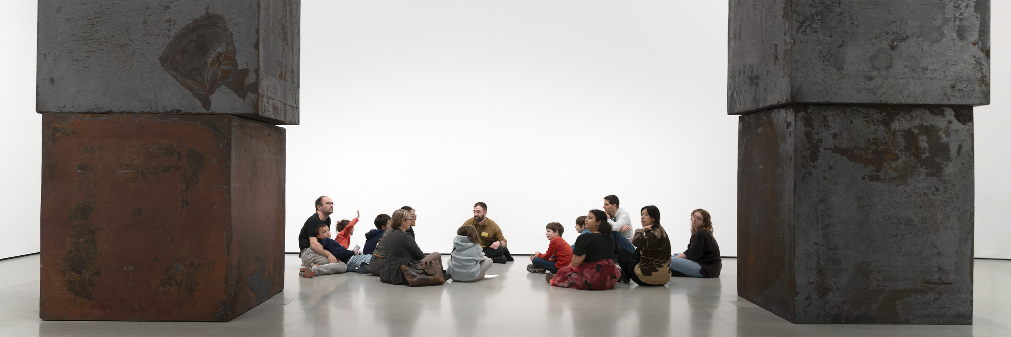 Photo: Martin SeckImage description: A group tour sits on the floor beside Richard Serra's sculpture Equal.