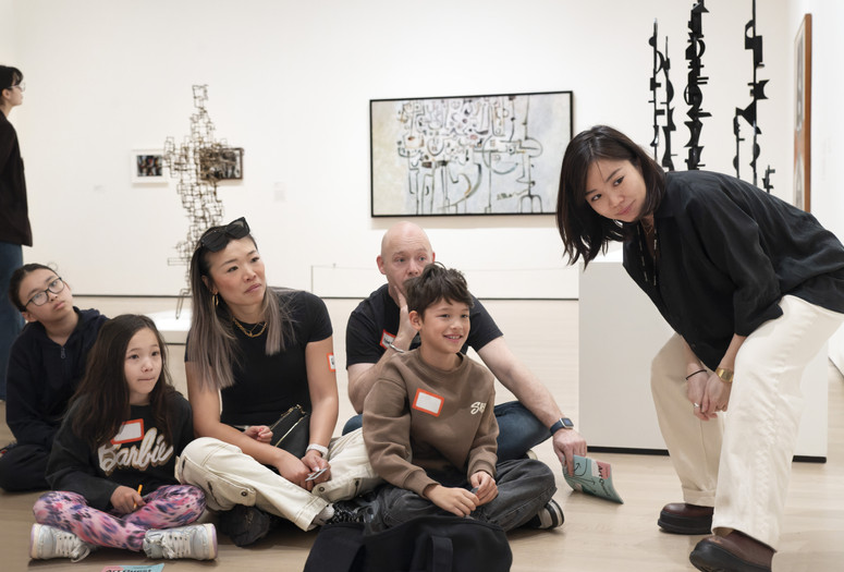 An instructor and families look at artworks together. Photo: Martin Seck
