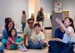 Photo: On White Wall, Inc.Image description: Instructor explains artwork to smiling families.