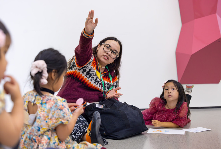 Photo: Bea MeseguerImage description: An educator and a child look upward at artwork together.