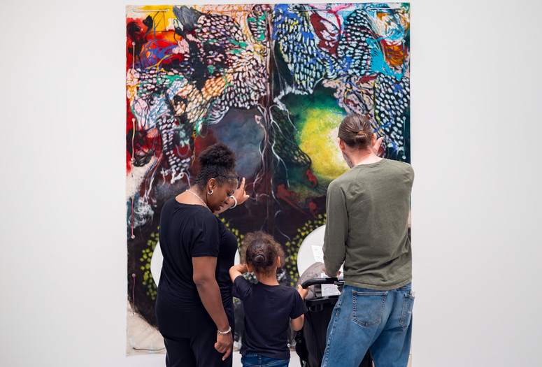 Photo: On White Wall Inc.Image description: A child looks at an artwork on the wall alongside two caregivers.