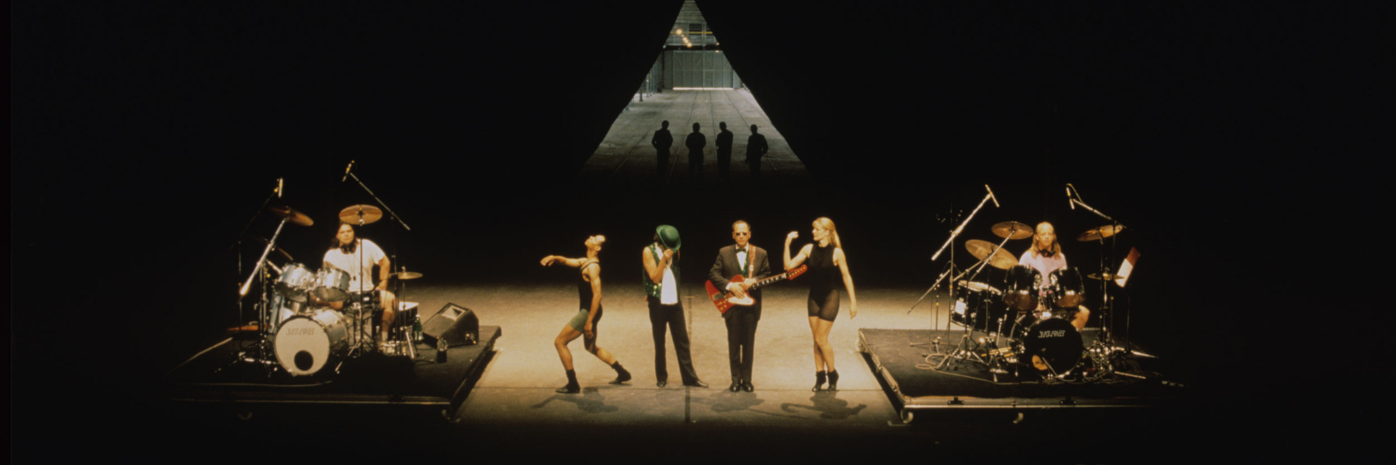 Mike Kelley, Anita Pace, Stephen Prina. Beat of the Traps. 1992. Performed in Expanded Art, Wiener Festwochen, The Remise, Vienna, Austria, 1992. Performers (from left): Jonathan “Butch” Norton, Carl Burkley, Alan Abelew, Stephen Prina, Anita Pace, M.B. Gordy. Photo: Karl Krauss. © Mike Kelley Foundation for the Arts. All Rights Reserved/VAGA at ARS, NY.⁠, Anita Pace, Stephen Prina