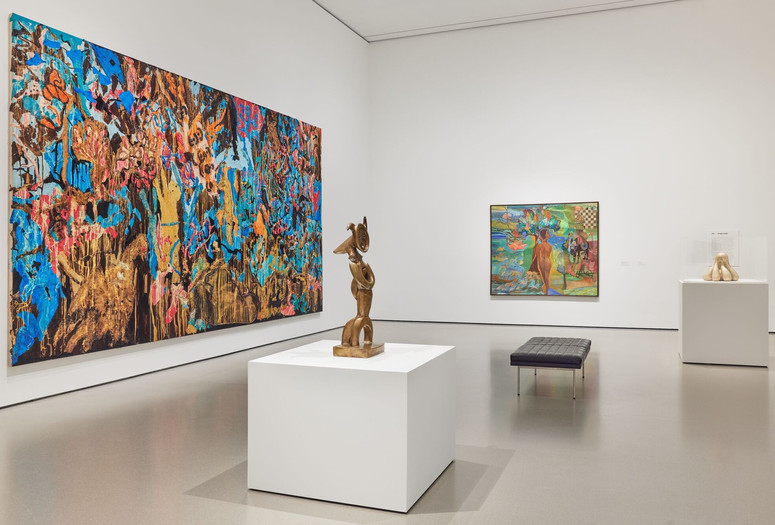 Credit: Installation view of the gallery Jungle Jungle, The Museum of Modern Art, New York, May 2, 2025–ongoing. Photo: Martin Parsekian. Image description: A photograph of a gallery installed with colorful large-scale paintings on the wall and bronze sculptures on white pedestals, with a black gallery bench in the center