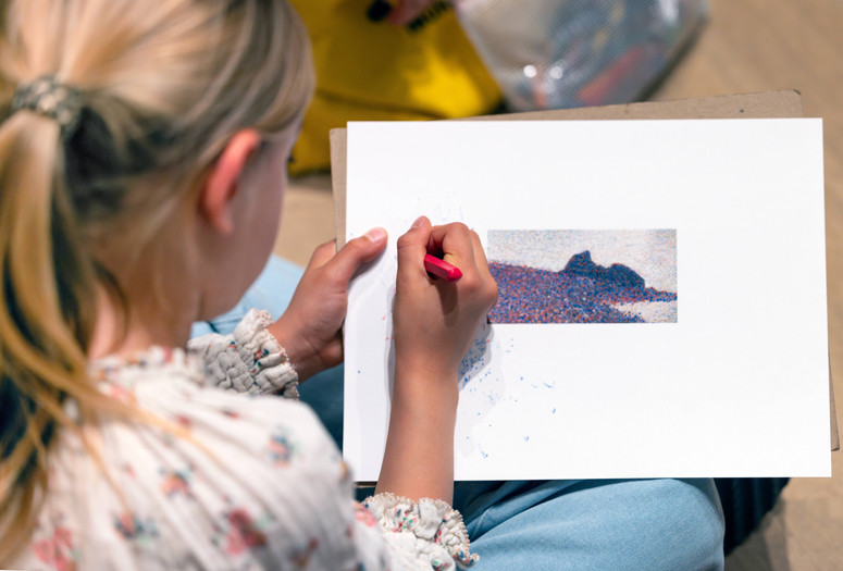 A child adds marks to an activity sheet that shows a pointillist painting. Photo: On White Wall, Inc.