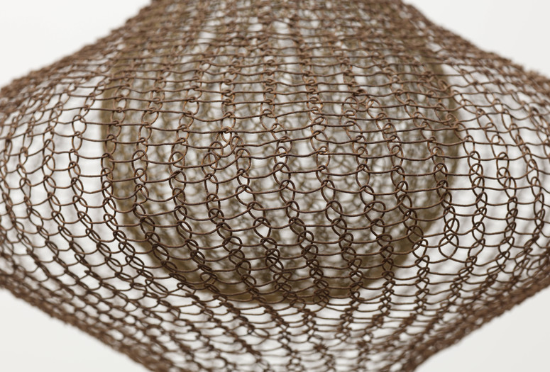Ruth Asawa. Untitled (S.398, Hanging Eight-Lobed, Four-Part, Discontinuous Surface Form within a Form with Spheres in the Seventh and Eighth Lobes). 1955. Brass, galvanized steel, and steel wire. The Museum of Modern Art, New York. Promised gift of Alice and Tom Tisch. © Estate of Ruth Asawa. Image description: A wire sculpture with a net-like pattern creates a bulbous shape. The metal wire is predominantly brown against a light background.
