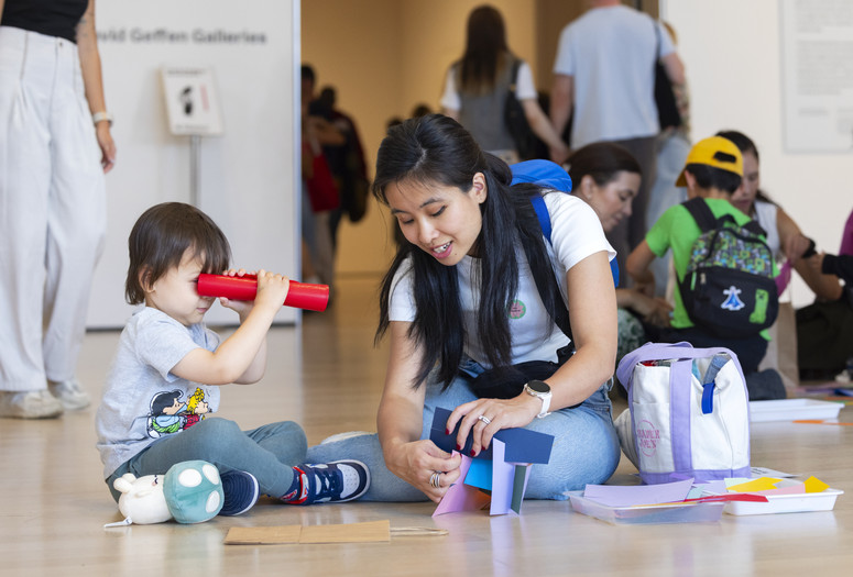 A child and an adult build a paper sculpture in the galleries during UNIQLO Family Day. Photo: On White Wall, Inc.