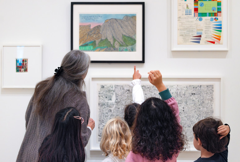 An educator and group of kids look closely at an artwork together. Photo: On White Wall, Inc.