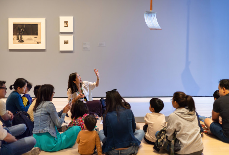An educator leads a conversation to a group of young children and their families in front of a sculpture. Photo: On White Wall Inc.