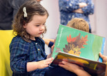 A child reads a picture book. The page shows different types of leaves. Photo: On White Wall, Inc.