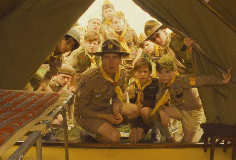 Moonrise Kingdom. 2012. USA. Directed by Wes Anderson. Courtesy Focus Features/Photofest Image description: A group of boy scouts and their troop leader crouch together at the opening of a canvas tent. They face the camera as they peer inside, with looks of disbelief.