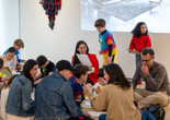 An educator smiles at a child in the galleries while looking at the child’s artwork. Photo: On White Wall, Inc.