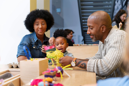 Parents and a child use recycled materials to create a creature in Art Lab. Photo: Martin Seck