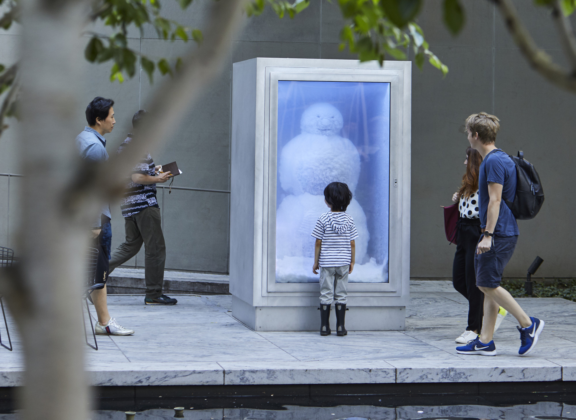 Visitors in The Abby Aldrich Rockefeller Sculpture Garden. Shown: Peter Fischli and David Weiss. Snowman. 1987/2016. Copper, aluminum, glass, water, coolant system. Courtesy Matthew Marks Gallery. © Peter Fischli and David Weiss. Photo: Gus Powell