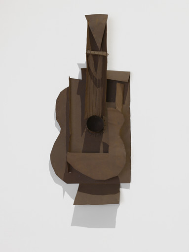 A brown, abstract metallic sculpture resembling a guitar is mounted on a white wall. The composition features overlapping shapes and textures. This is an AI generated description. To give feedback, email ai@moma.org.