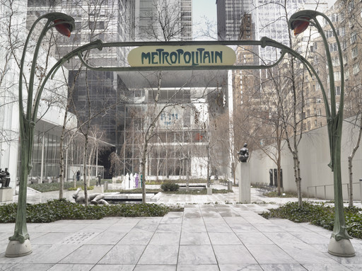 A garden area with bare trees and a grey marble ground, with a "Metropolitain" subway sign and arch framed by two green ornate lamp posts. In the background, sculptures and a rectangular pool of water are surrounded by city buildings. This is an AI generated description. To give feedback, email ai@moma.org.