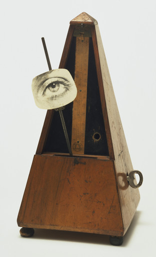 A wooden metronome with a pendulum holds a black-and-white photograph of an eye. The predominant colors are brown and black. This is an AI generated description. To give feedback, email ai@moma.org.