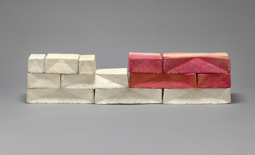 The image shows a structure made of rectangular blocks. The blocks are mainly off-white and beige, with four blocks on the right that are red and orange. This is an AI generated description. To give feedback, email ai@moma.org.