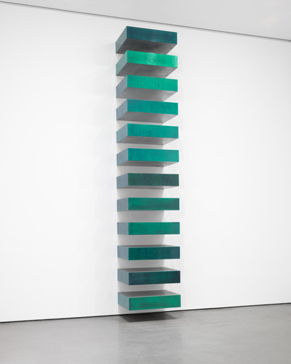Vertical sculpture featuring stacked horizontal metallic blocks in varying shades of green. The structure is displayed against a plain white wall. This is an AI generated description. To give feedback, email ai@moma.org.